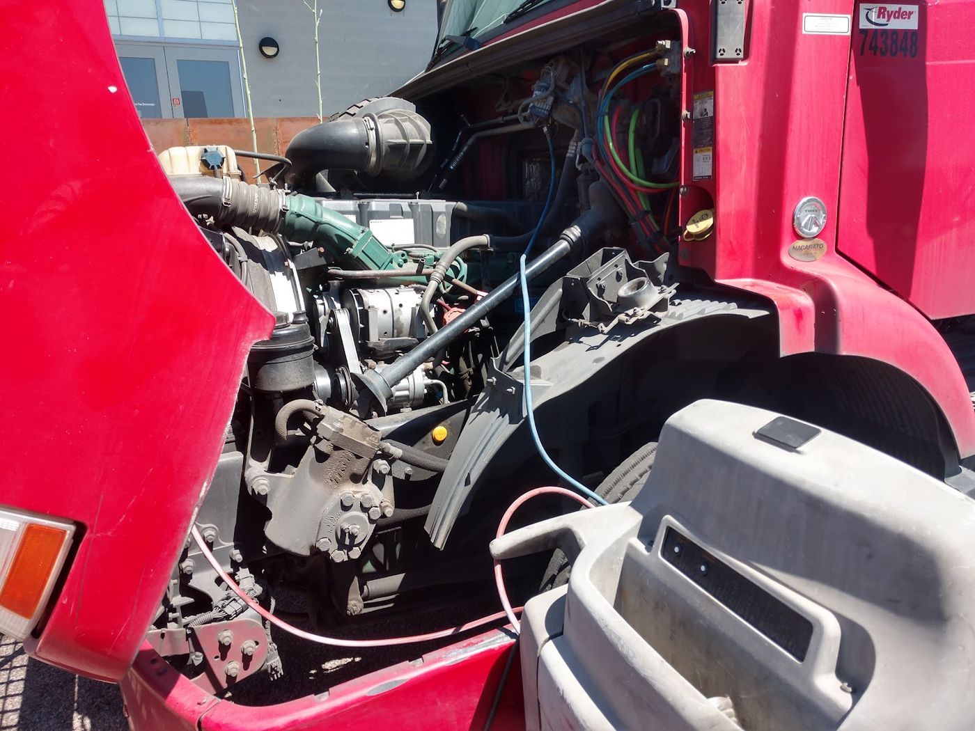 A red truck with the hood open and the engine exposed